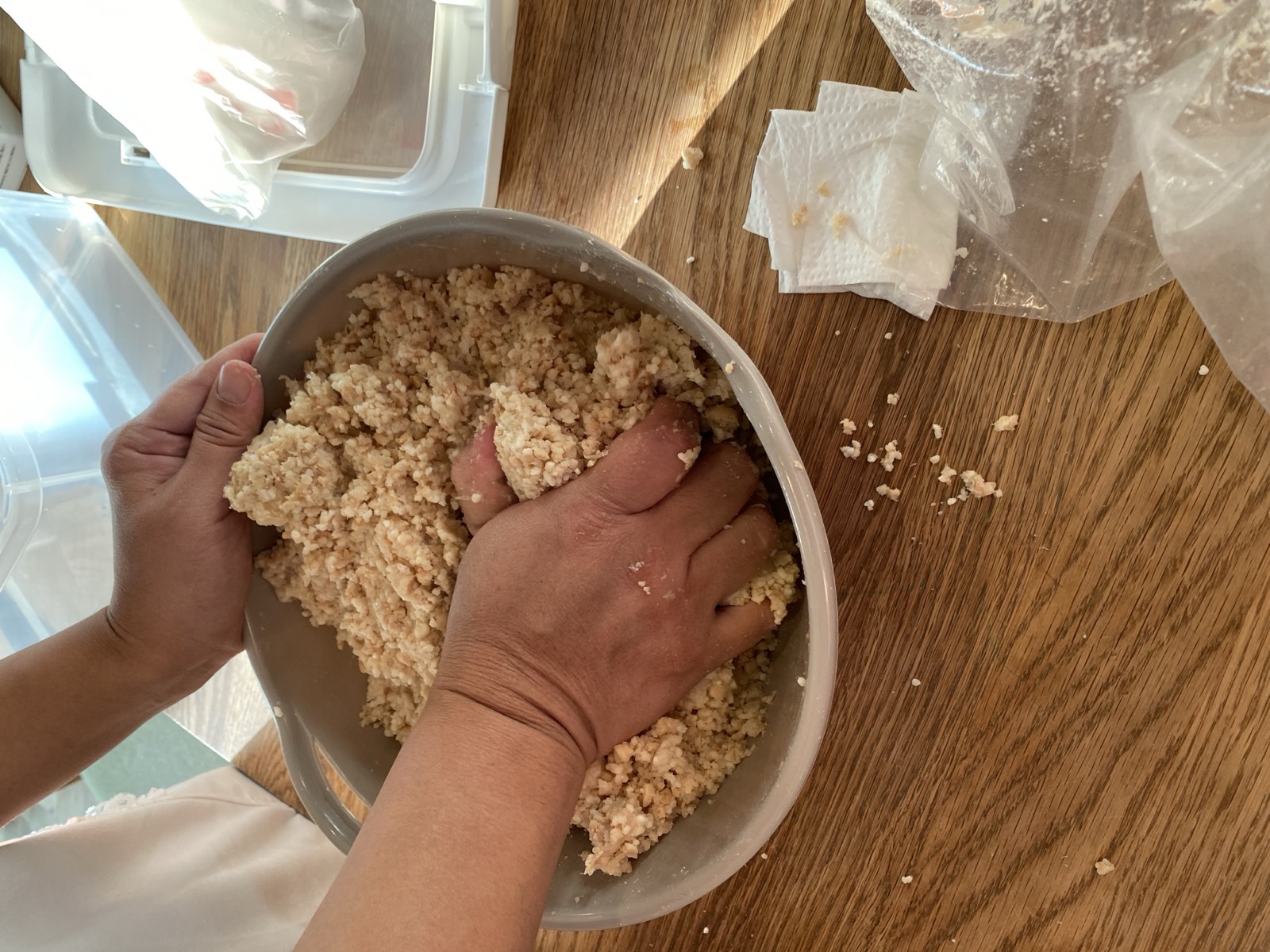 ボウルの中で、つぶした大豆と麹を手で混ぜているところ