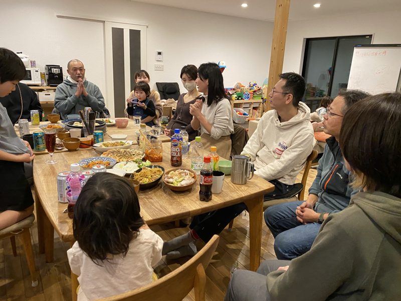夜のリビングで、大人と子どもが食卓を囲んでいる写真